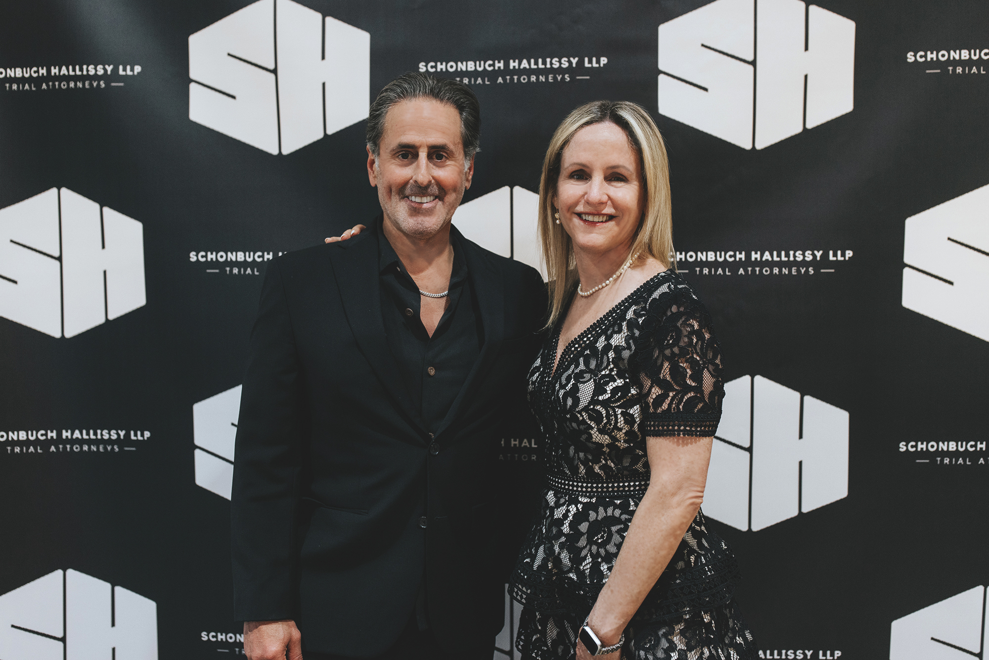 Photo of Mike Schonbuch and Erin Hallissy agains a backdrop of SH logos; Happy Anniversary to Schonbuch Hallissy LLP